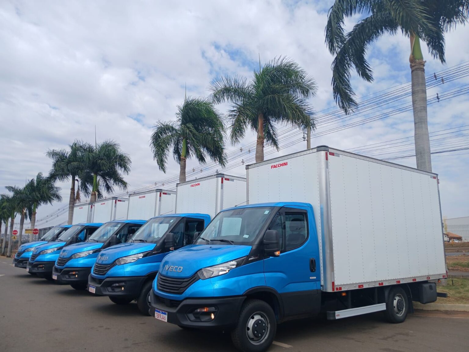 Caminhões e vans azuis da Hawk Transportes em pátio operacional